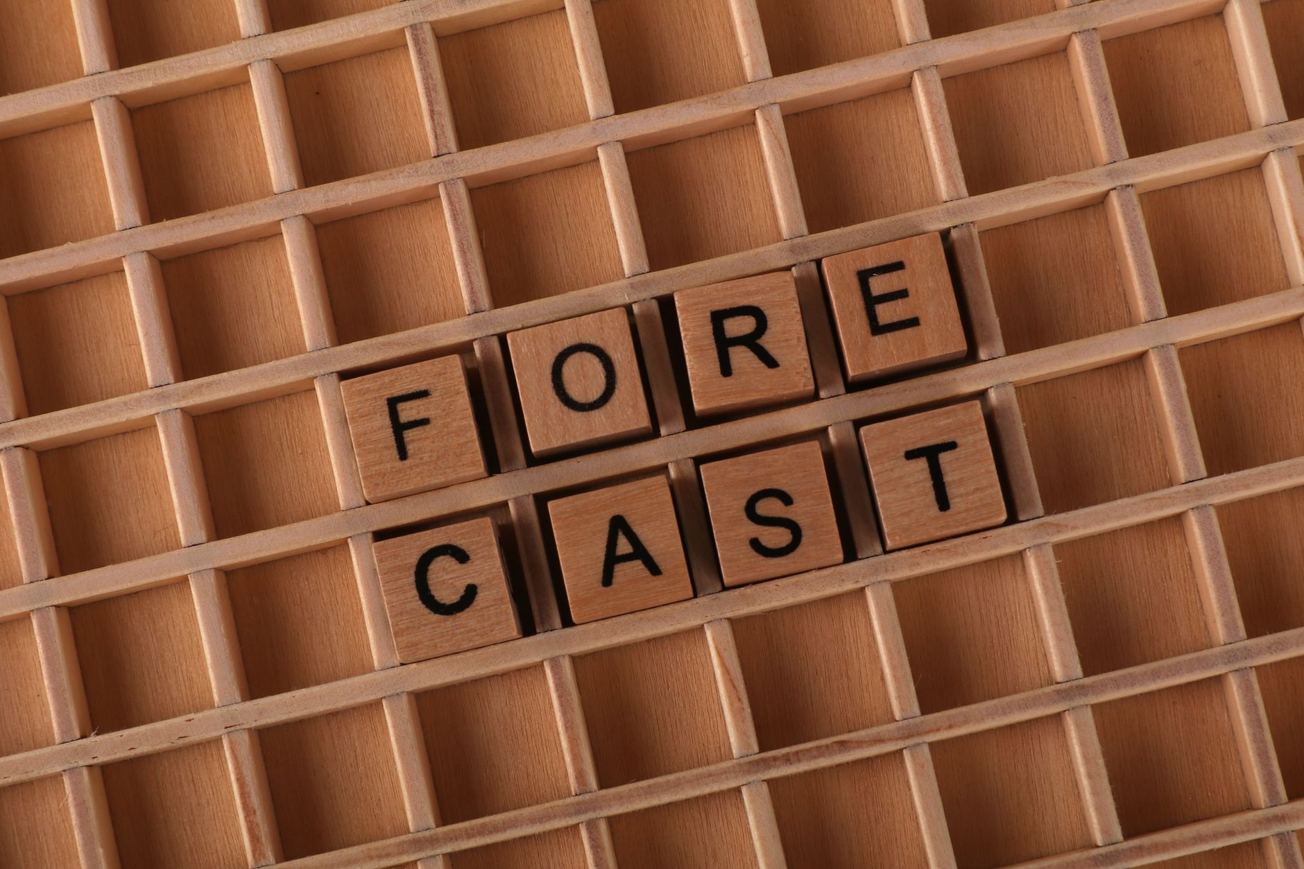 Wooden tiles spelling 'forecast' arranged on a wooden grid, perfect for business or prediction themes.