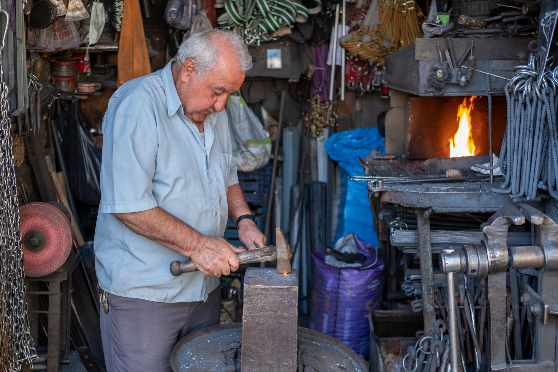 Elderly blacksmith working at an anvil in a traditional forge workshop in Şanlıurfa, Türkiye.