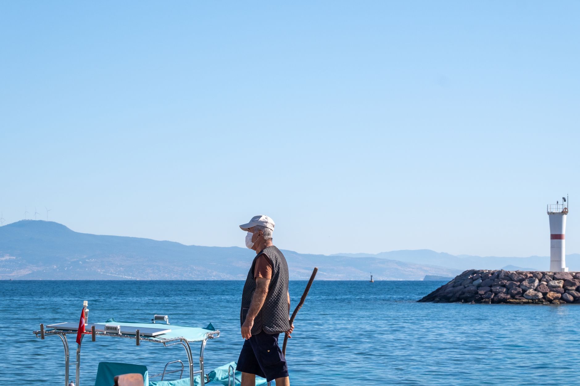 Elderly man standing on a boat by the Foça lighthouse in İzmir, Türkiye.