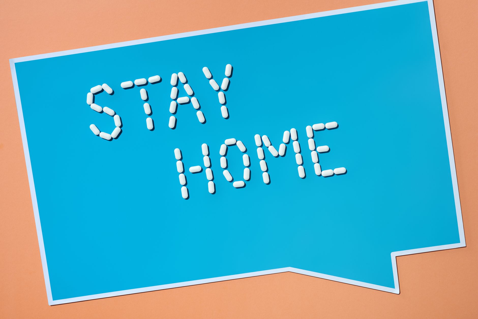 Creative conceptual image showing 'Stay Home' message made of pills on blue background.