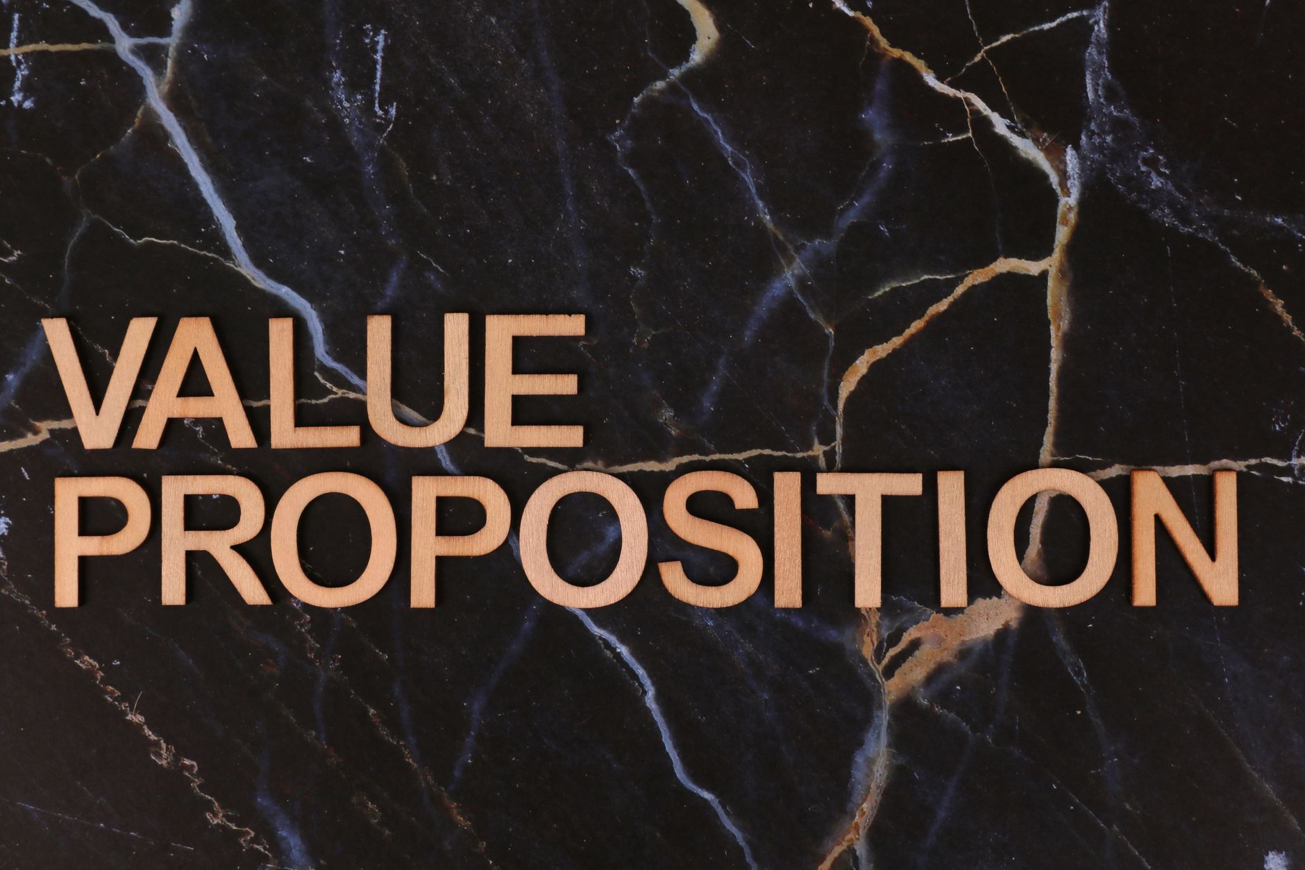 Wooden letters spelling 'Value Proposition' on a marble background, symbolizing business strategy.