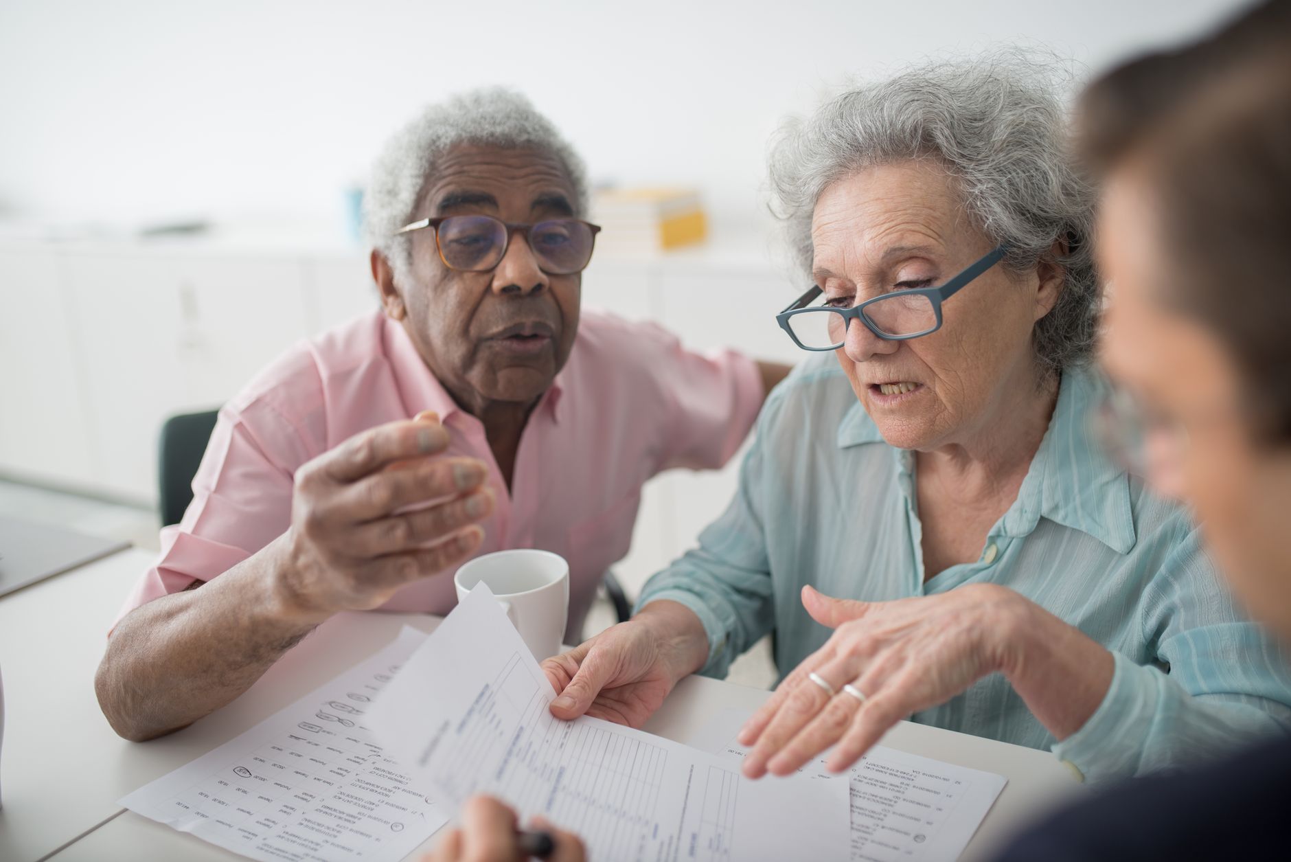 Elderly couple discussing financial documents with a consultant in an office setting.